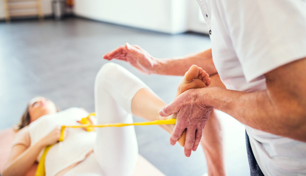 Unrecognizable senior physiotherapist working with a female patient.