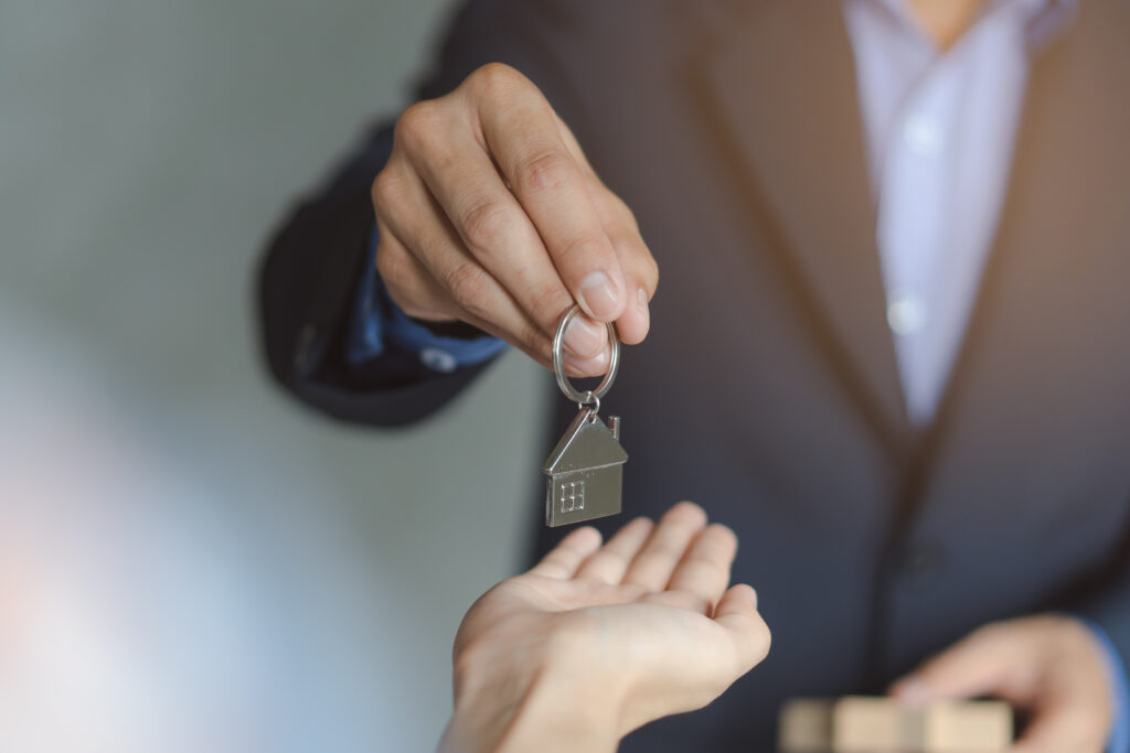 close up view hand of property realtor / landlord giving key hou